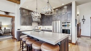 A kitchen with a large island, bar stools, and modern appliances. - Ski-in ski-out home w/ large kitchen, hot tub & great location (Avon)