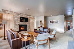 Ein modernes Wohnzimmer mit Kamin aus Stein, Ledersofas und einem Flachbildfernseher.