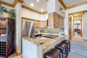 A modern kitchen with a central island, stainless steel appliances, wooden cabinets, and a built-in oven. - Ski-In/Ski-Out Villa w/ Fireplace, High-Speed WiFi & Shared Hot Tub, Pool, & W/D (Vail)