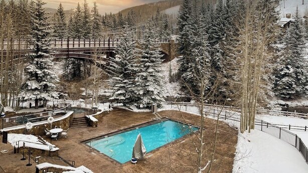 Area piscina con pavimento in legno, poltrona prendisole e piccola vasca.