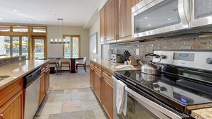 Une cuisine moderne avec des meubles en bois, des appareils électroménagers en acier inoxydable et un pare-feu en pierre.