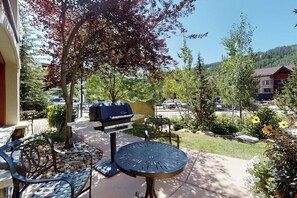 An outdoor patio with a grill, seating, and a view of a parking area and buildings. - Chalet in Ski-In/Ski-Out Complex w/Fireplace, Fast WiFi, & Shared Pool/Hot Tubs (Vail)