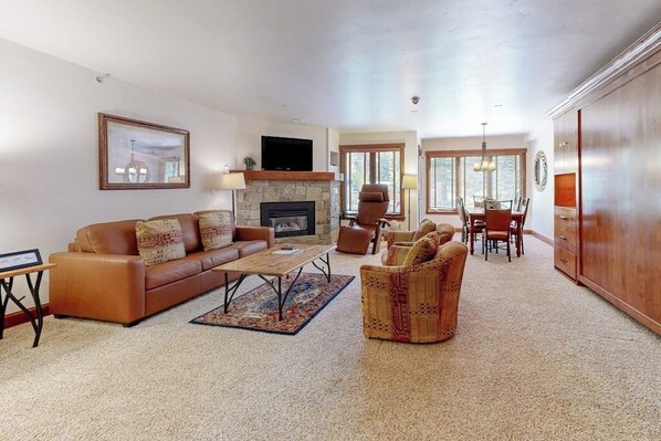 A spacious living room with a fireplace, leather sofa, and a dining area with chairs and a table. - Chalet in Ski-In/Ski-Out Complex w/Fireplace, Fast WiFi, & Shared Pool/Hot Tubs (Vail)