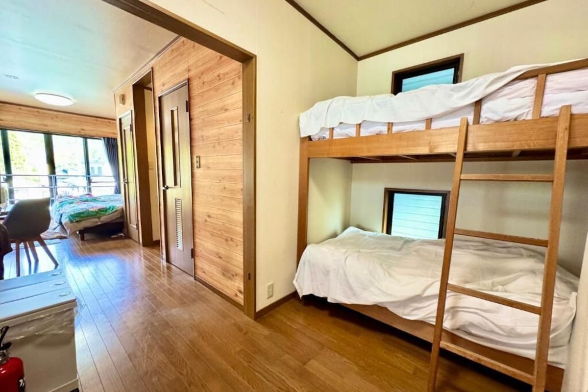 A room with bunk beds, a desk, and a chair.