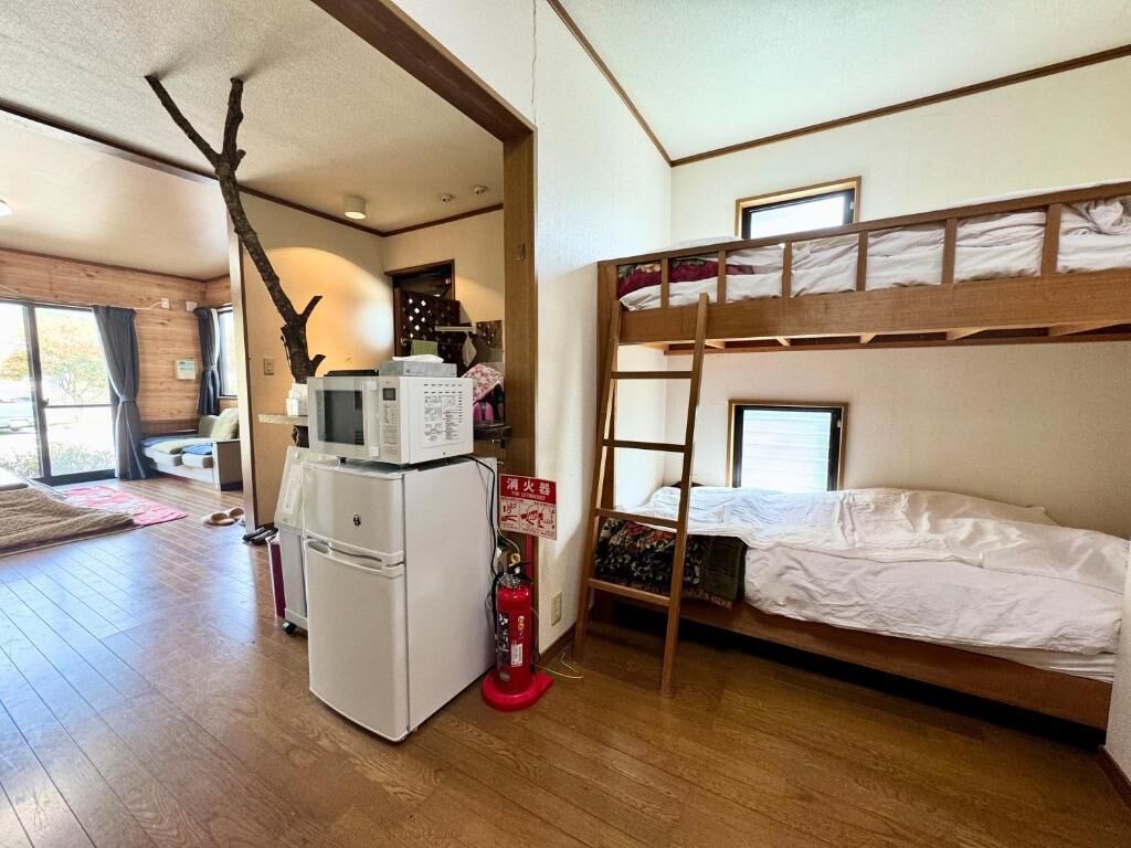 A bunk bed room with a refrigerator, microwave, and a fire extinguisher.