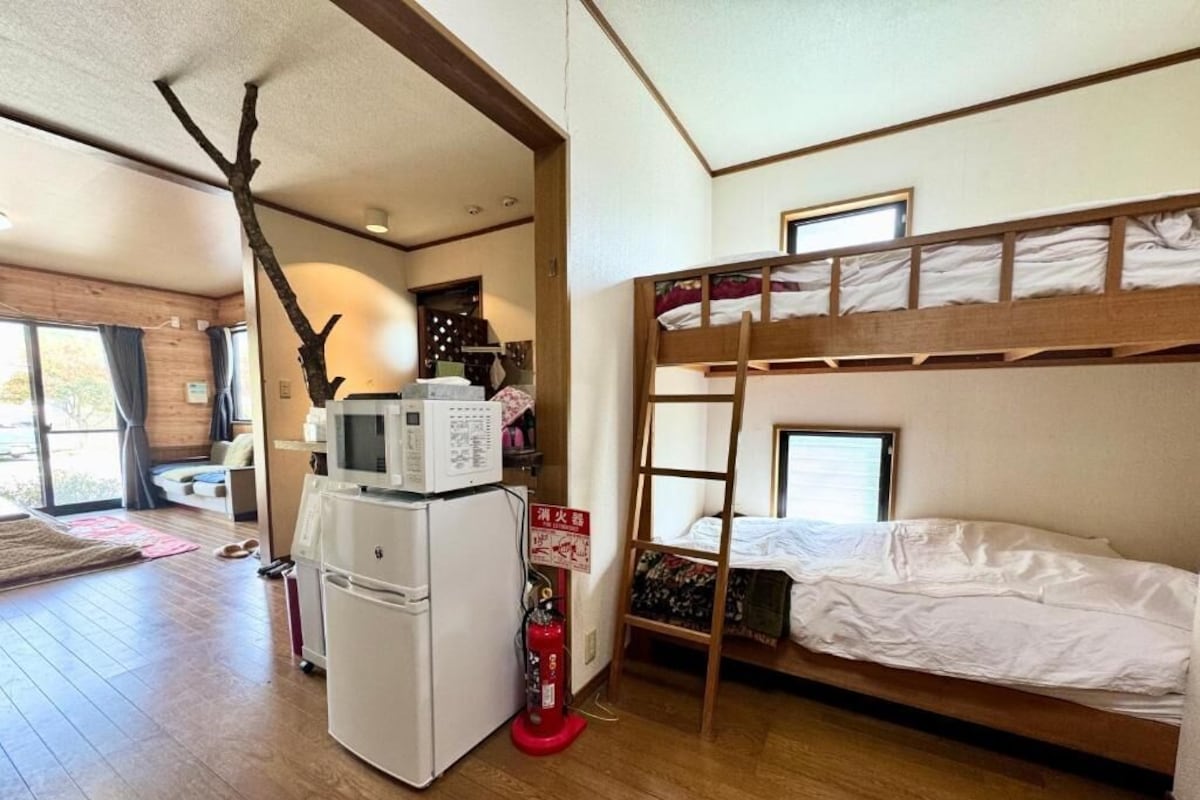 A bunk bed room with a refrigerator, microwave, and a fire extinguisher.