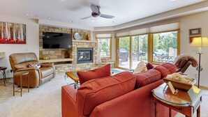 Una sala de estar con chimenea de piedra, sofá de cuero y televisor de pantalla plana.