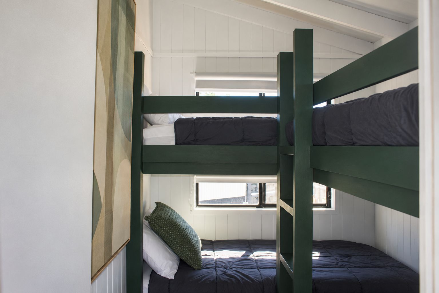 A bunk bed room with white walls and a window.