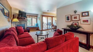 Una sala de estar con un sofá rojo, un televisor y una chimenea.