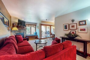 A living room with a red sofa, a television, and a fireplace. - Mountainview Condo in Ski/In-Ski-Out Building w/Free WiFi, Shared Pool/Hot Tubs (Vail)