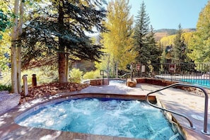 A hot tub surrounded by trees, a pool, and a fenced area. - Ski-in/out, hotel-style studio w/ high-speed WiFi & shared pool, hot tubs, W/D (Vail)