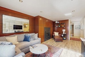 Ein modernes Wohnzimmer mit Sofa, Couchtisch, Kamin und einem großen Spiegel.