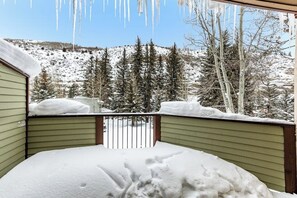 Ein mit Schnee bedeckter Balkon mit Blick auf eine verschneite Landschaft und Bäume.