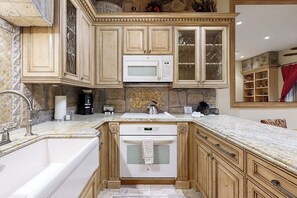 A kitchen with wooden cabinets, a microwave, a stove, and a sink. - Eclectic garden-level ski-in/ski-out condo with pool, hot tubs, W/D & fast WiFi (Vail)