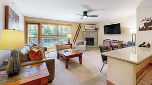 Ein Wohnzimmer mit Kamin, Deckenventilator und Wand-Fernseher.