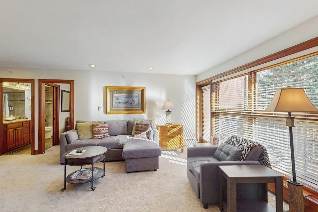 A living room with a sectional sofa, a round coffee table, a lamp, and a painting on the wall.