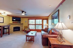 A living room with a fireplace, a sofa, a coffee table, and a TV. - Ski-in/out, mountain view condo w/ fireplace, fast WiFi, shared pool/WD/hot tub (Vail)