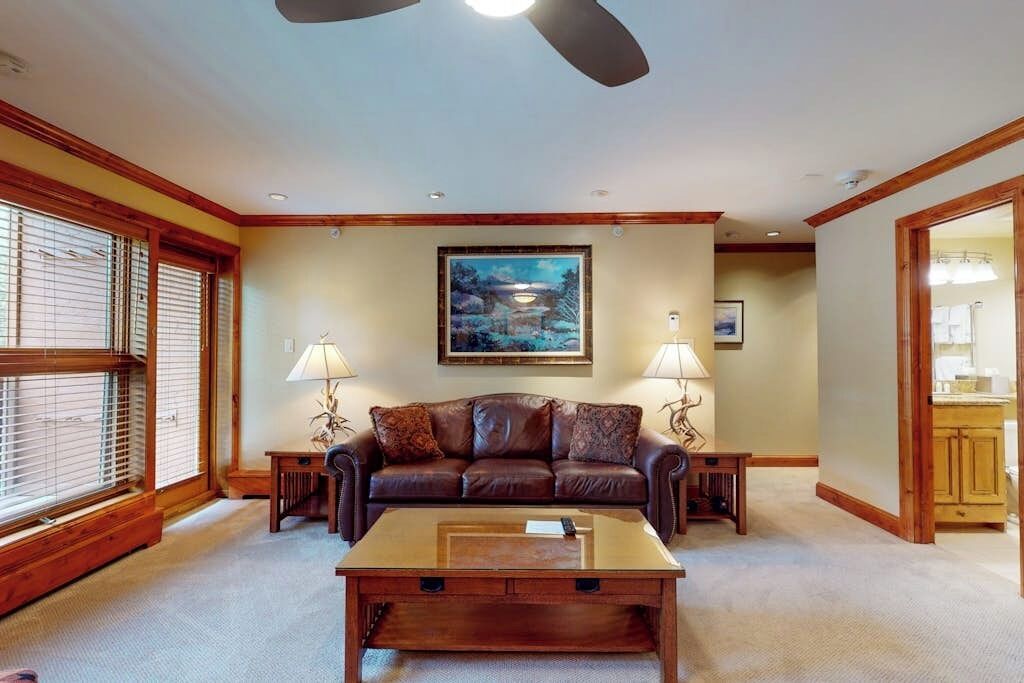A living room with a brown leather sofa, a glass coffee table, and wooden accents.