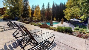 A poolside area with lounge chairs, a pool, and surrounding trees. - Ski-in/out, mountain view condo w/ fireplace, fast WiFi, shared pool/WD/hot tub (Vail)