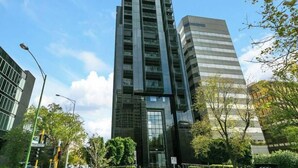 A modern high-rise building with a glass facade, surrounded by trees and other buildings. - Caleb - Unique Melbourne Experience *WiFi Park Gym (Melbourne)