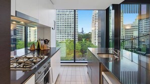 Una cocina moderna con un ventanal grande, vista a la ciudad y electrodomésticos de acero inoxidable.