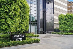 Een modern gebouw met een bord waarop 'LEOPOLD 470' staat, omgeven door verzorgde beplanting.