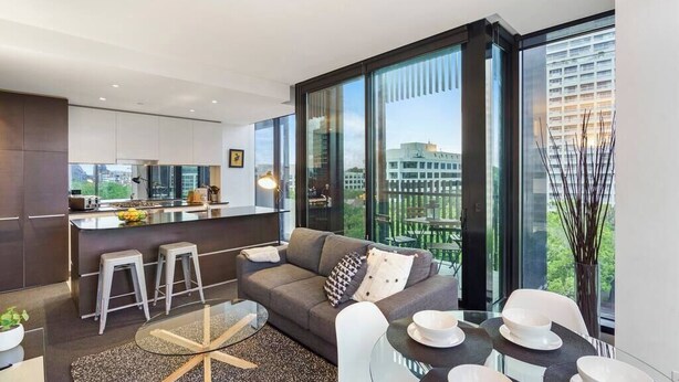 Un espacio habitable moderno con cocina, comedor y zona de estar junto a amplios ventanales.