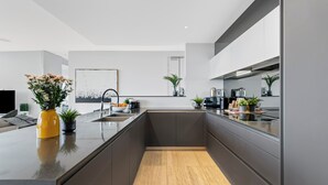 Una cocina moderna con una isla central, armarios oscuros y suelo de madera.