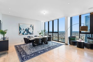 Ein geräumiges Wohnzimmer mit Essbereich, großen Fenstern und Blick auf die Stadt.
