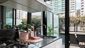 Cocina moderna con estufa a gas, un lavamanos y ventana con vistas a la ciudad.