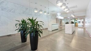 Un vestíbulo moderno con paredes de mármol, plantas en macetas y un mostrador de recepción.