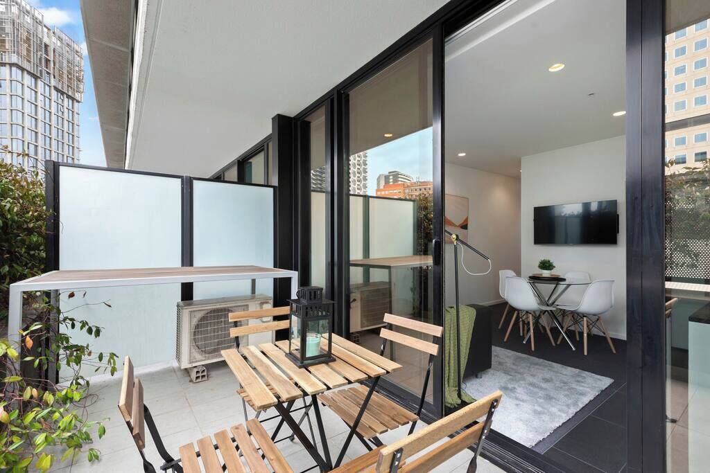 En moderne lejlighed med balkon, spiseområde og TV i stuen.