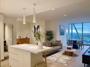 A modern kitchen with a central island, a dining area with a view, and a living space with a sofa and a coffee table. - Jaw-dropping views from executive city residence (Melbourne)
