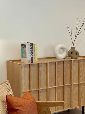 A wooden console with books, a white circular object, and a vase with branches. - Jaw-dropping views from executive city residence (Melbourne)