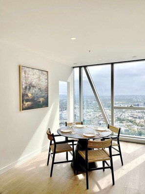 A dining area with a round table, chairs, and a large window offering a city view. - Jaw-dropping views from executive city residence (Melbourne)