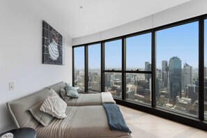 Ein modernes Zimmer mit großem Fenster, einer Couch und Blick auf die Stadt.