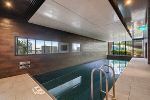 Ein Hallenbad mit Tiefenhinweis, einem Sprungverbotsschild und einem Ausgangsschild.