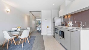 Een moderne keuken met een eethoek, witte kastjes en een zichtbare koelkast.