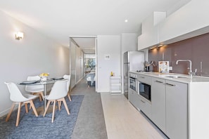 Eine moderne Küche mit Essbereich, weißen Schränken und einem sichtbaren Kühlschrank.
