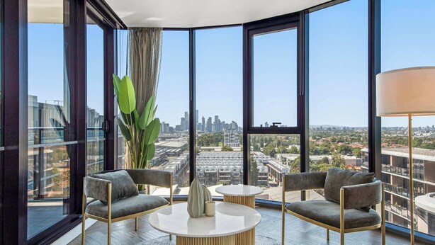 A modern room with large windows, a round coffee table, two armchairs, and a floor lamp.