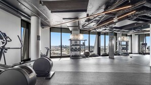 Ein modernes Fitnessstudio mit Trainingsgeräten, großen Fenstern und Blick auf die Stadt.