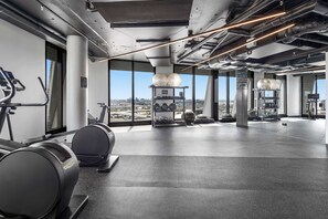A modern gym with exercise equipment, large windows, and a city view. - Ultralux City Townhouse with Parking, Gym + Views (West Melbourne)