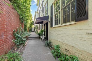 A narrow alleyway with a brick wall on one side and a building with a window and awning on the other. - Gorgeous Botanic Gardens Retreat with Parking (South Yarra)