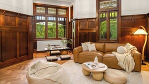 A room with a brown leather sofa, a round coffee table, a bean bag, and a dining table with chairs. - Luxury Seaside Estate with Pool & Garden Oasis (Brighton)