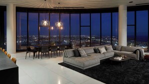 Uma sala de estar moderna com ampla vista para a cidade, sofá seccional, área de jantar e design de teto único.
