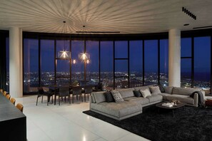Ein modernes Wohnzimmer mit großem Stadtblick, einer Eckcouch, Essbereich und einem außergewöhnlichen Deckenstil.