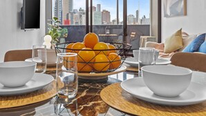 Una sala de estar moderna con vista a la ciudad, una mesa de comedor con frutero y un sofá.