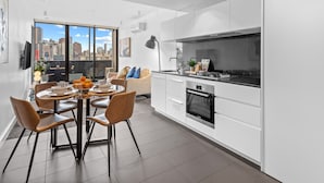 Un apartamento moderno con comedor, cocina y un amplio ventanal con vistas a la ciudad.