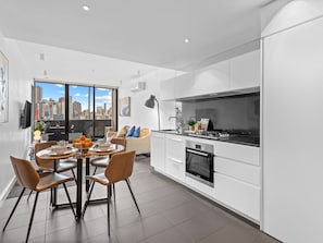 Eine moderne Wohnung mit Essbereich, Küche und einem großen Fenster mit Blick auf die Stadt.
