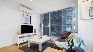 Een moderne woonkamer met een flatscreen-tv, witte meubels, een groot raam en een decoratief gewei.